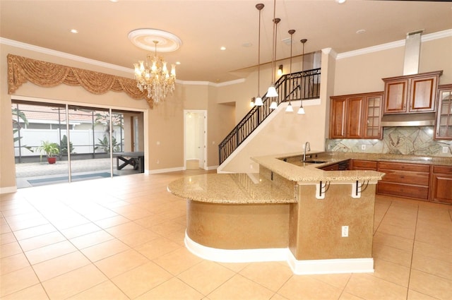 kitchen featuring ornamental molding, sink, light stone countertops, and a breakfast bar