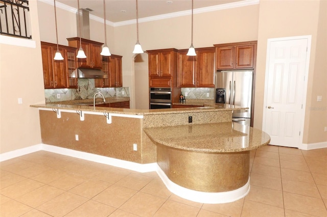 kitchen featuring kitchen peninsula, light stone counters, decorative light fixtures, and appliances with stainless steel finishes