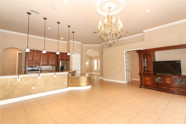 kitchen featuring appliances with stainless steel finishes, hanging light fixtures, light stone countertops, and ornamental molding