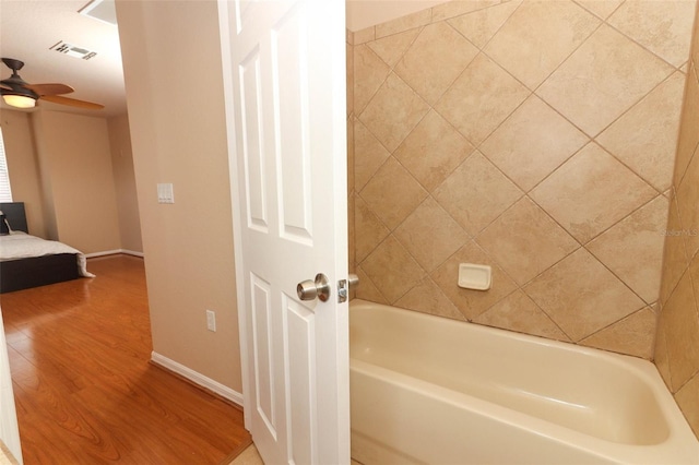 bathroom with hardwood / wood-style floors, ceiling fan, and a washtub