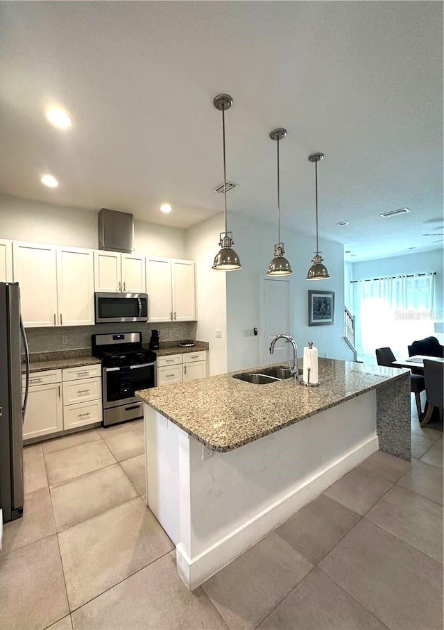 kitchen featuring stone counters, light tile patterned flooring, decorative light fixtures, stainless steel appliances, and sink