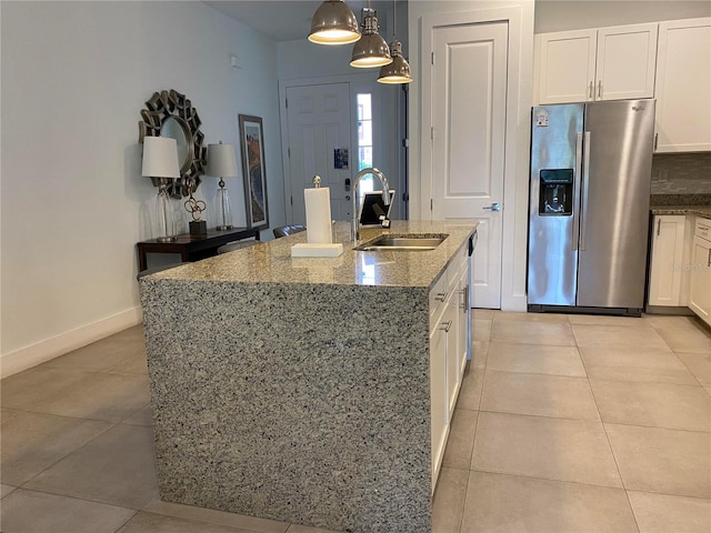 kitchen featuring a center island with sink, light tile patterned floors, sink, and stainless steel refrigerator with ice dispenser