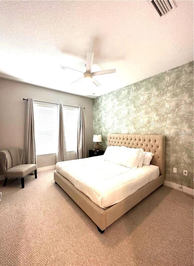 bedroom with ceiling fan, a textured ceiling, and carpet flooring