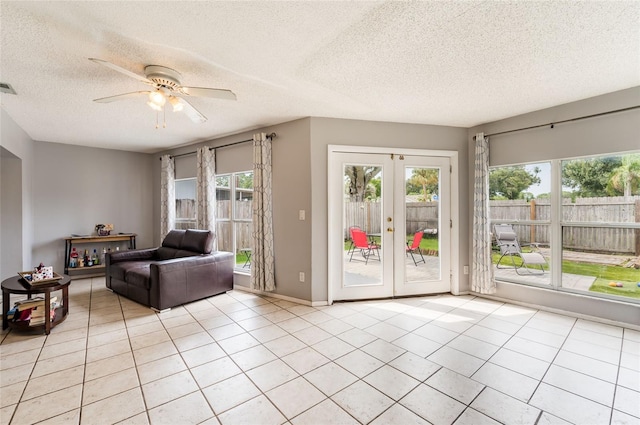 tiled living room featuring ceiling fan, french doors, and a textured ceiling