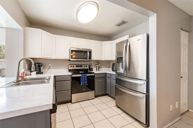 kitchen with stainless steel appliances, light tile patterned floors, white cabinets, gray cabinets, and sink