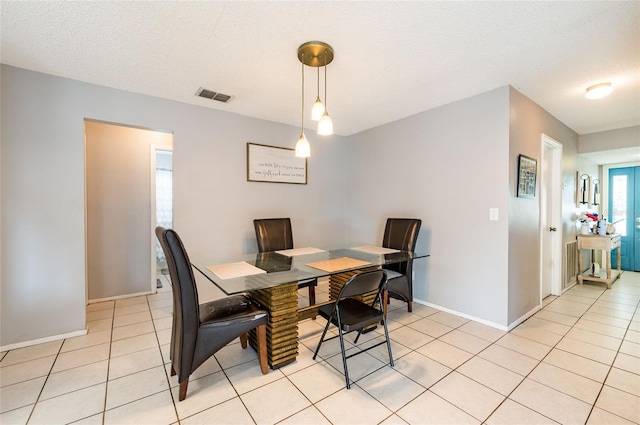 dining area featuring a textured ceiling and light tile patterned floors