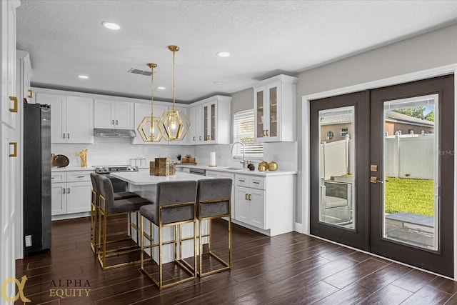 kitchen featuring a wealth of natural light, decorative light fixtures, refrigerator, and a kitchen island