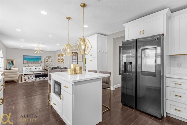 kitchen with a center island, dark wood-type flooring, white cabinetry, pendant lighting, and black appliances