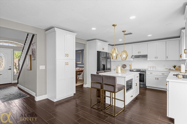 kitchen with stainless steel appliances, dark hardwood / wood-style floors, pendant lighting, a kitchen island, and a breakfast bar