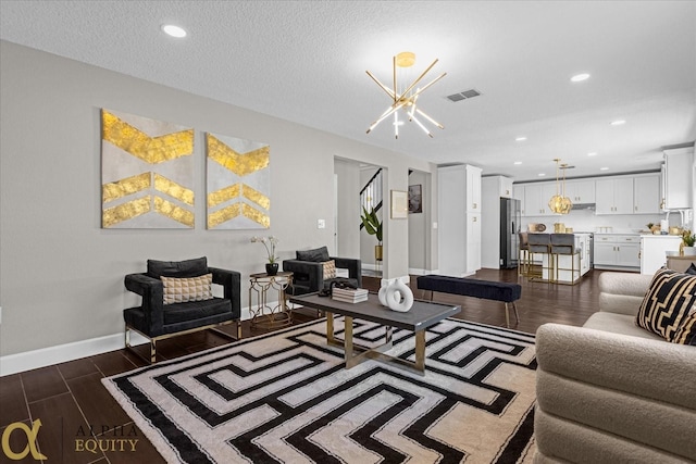 living room with sink, a textured ceiling, an inviting chandelier, and dark hardwood / wood-style floors