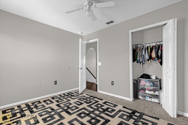 carpeted bedroom with a textured ceiling, a closet, and ceiling fan