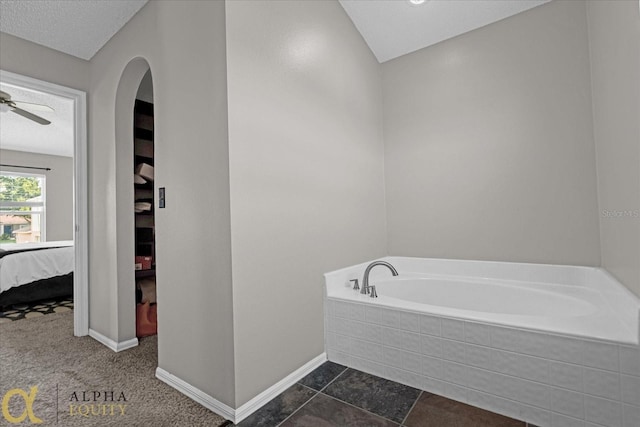 bathroom with a bathing tub, ceiling fan, a textured ceiling, and tile patterned flooring