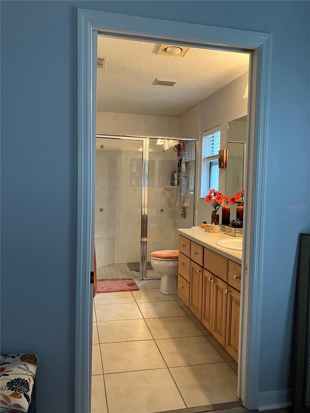 bathroom featuring a textured ceiling, vanity, an enclosed shower, toilet, and tile patterned floors