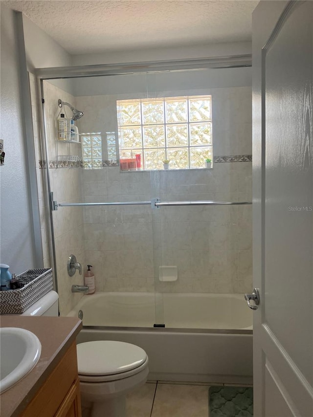 full bathroom with toilet, tile patterned floors, combined bath / shower with glass door, vanity, and a textured ceiling