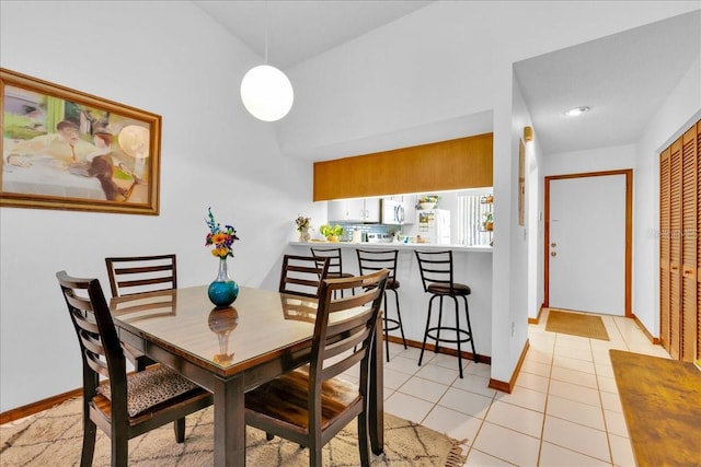 dining room with high vaulted ceiling and light tile patterned floors