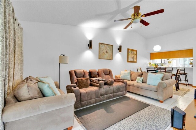 tiled living room featuring ceiling fan and lofted ceiling