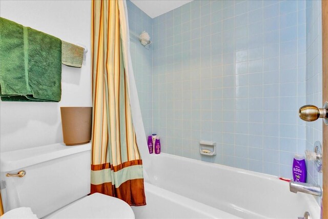 bathroom featuring toilet and shower / bath combination with curtain