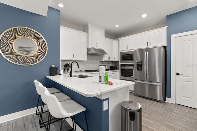 kitchen featuring stainless steel appliances, light hardwood / wood-style flooring, white cabinetry, tasteful backsplash, and sink