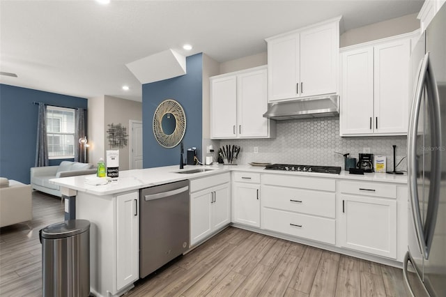 kitchen with sink, appliances with stainless steel finishes, decorative backsplash, light hardwood / wood-style floors, and white cabinets