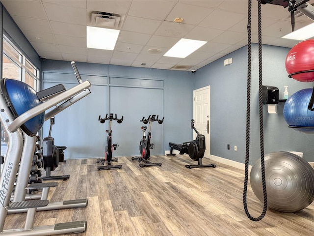 workout room featuring a paneled ceiling and wood-type flooring