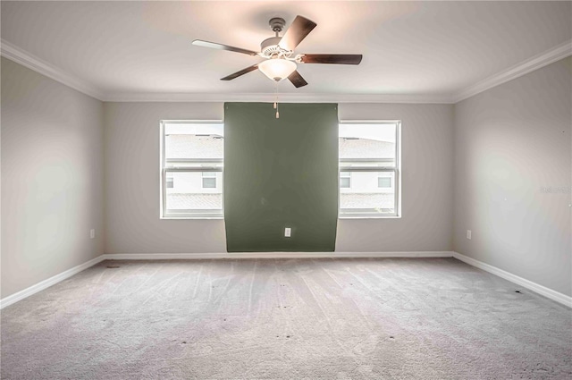 carpeted spare room with ceiling fan, a healthy amount of sunlight, and ornamental molding