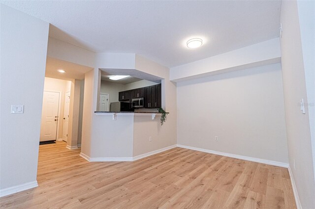 interior space featuring refrigerator, light hardwood / wood-style floors, and kitchen peninsula