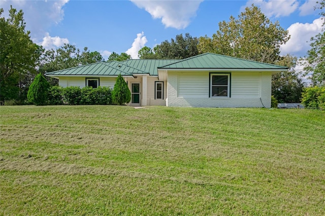ranch-style home featuring metal roof, a front yard, and brick siding