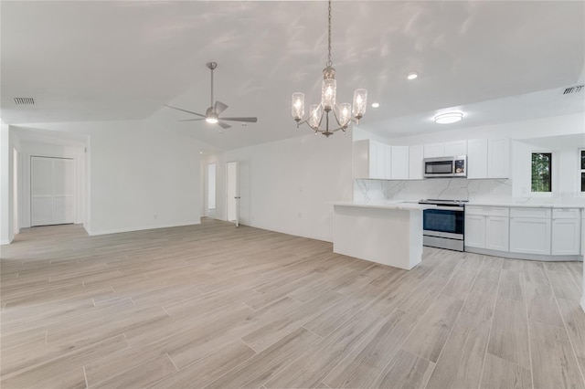 kitchen with decorative light fixtures, white cabinets, decorative backsplash, stainless steel appliances, and light wood-type flooring