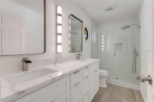 bathroom featuring vanity, a shower with door, and toilet