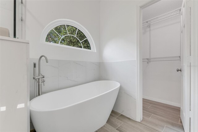 bathroom featuring a tub to relax in and tile walls