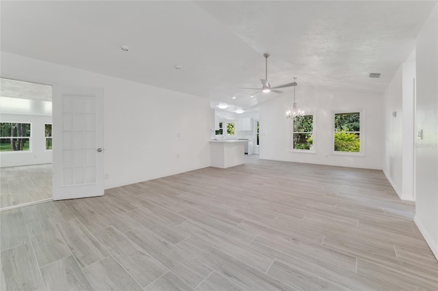 unfurnished living room featuring lofted ceiling, ceiling fan with notable chandelier, light hardwood / wood-style flooring, and a healthy amount of sunlight