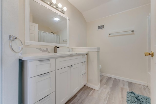 bathroom with lofted ceiling, toilet, a shower with curtain, vanity, and hardwood / wood-style floors