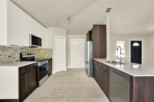 kitchen featuring light tile patterned flooring, stainless steel appliances, backsplash, sink, and dark brown cabinetry