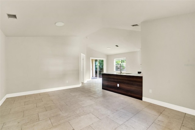 unfurnished room with lofted ceiling, light tile patterned flooring, and sink