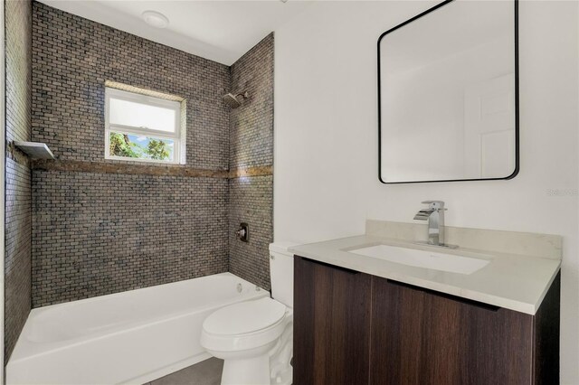 full bathroom featuring tiled shower / bath combo, vanity, and toilet