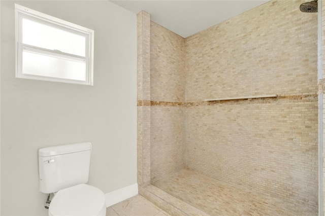 bathroom featuring tile patterned floors, a tile shower, and toilet