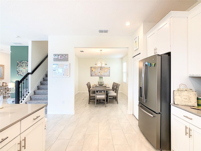 kitchen featuring white cabinetry, stainless steel fridge, and hanging light fixtures