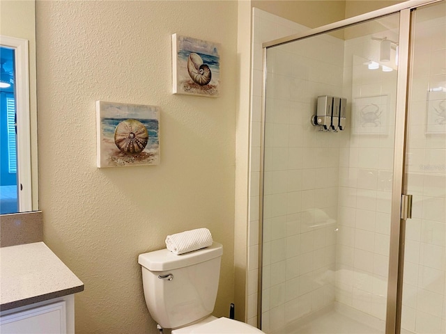 bathroom featuring vanity, an enclosed shower, and toilet