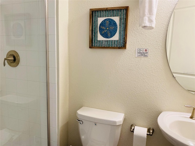 bathroom with sink, toilet, and tiled shower