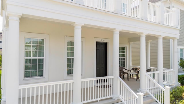 view of exterior entry with a balcony and a porch