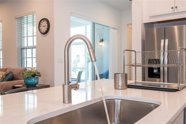 kitchen featuring a healthy amount of sunlight, light stone countertops, and white cabinetry