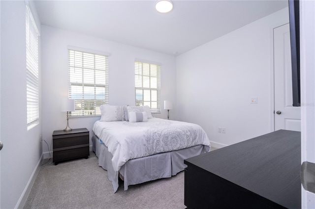 bedroom with multiple windows and light carpet