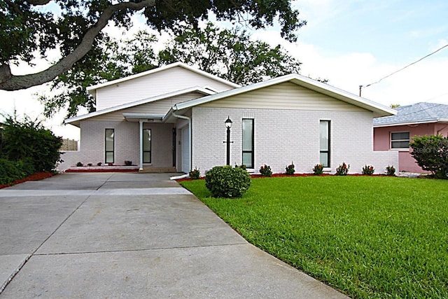 view of front of house featuring a front lawn, brick siding, and driveway