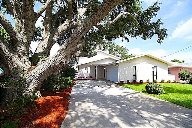 view of front of property with a garage, brick siding, concrete driveway, and a front lawn