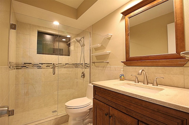 bathroom featuring toilet, vanity, tasteful backsplash, tile walls, and a shower with shower door