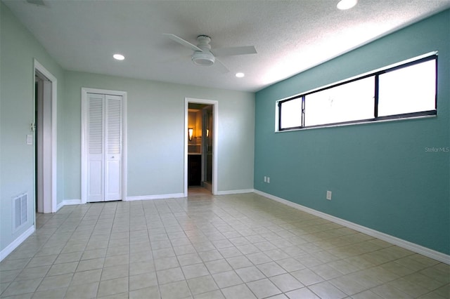 unfurnished bedroom featuring a textured ceiling, light tile patterned flooring, ceiling fan, and a closet