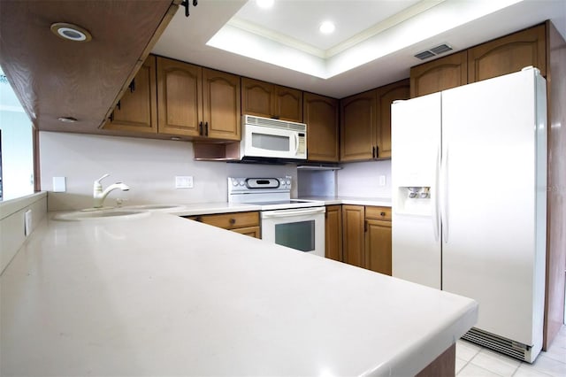 kitchen featuring ornamental molding, white appliances, sink, a tray ceiling, and light tile patterned flooring