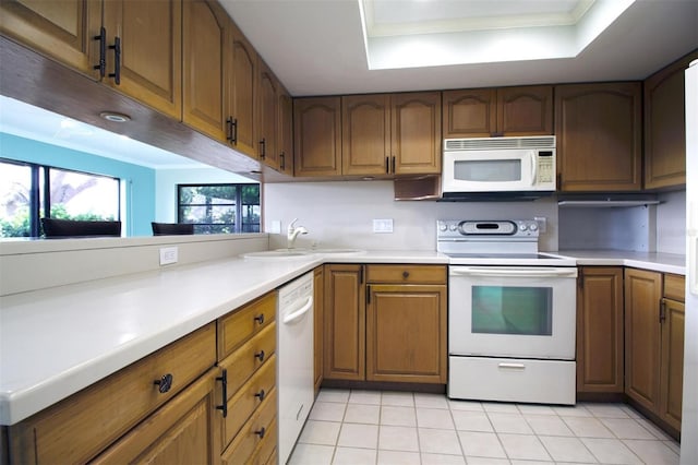 kitchen featuring light tile patterned floors, crown molding, white appliances, sink, and a tray ceiling