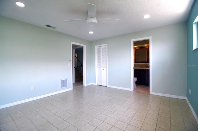 unfurnished bedroom featuring a textured ceiling, connected bathroom, ceiling fan, and a closet