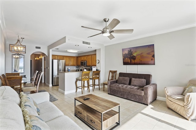 living room featuring light tile patterned floors, ceiling fan with notable chandelier, and ornamental molding